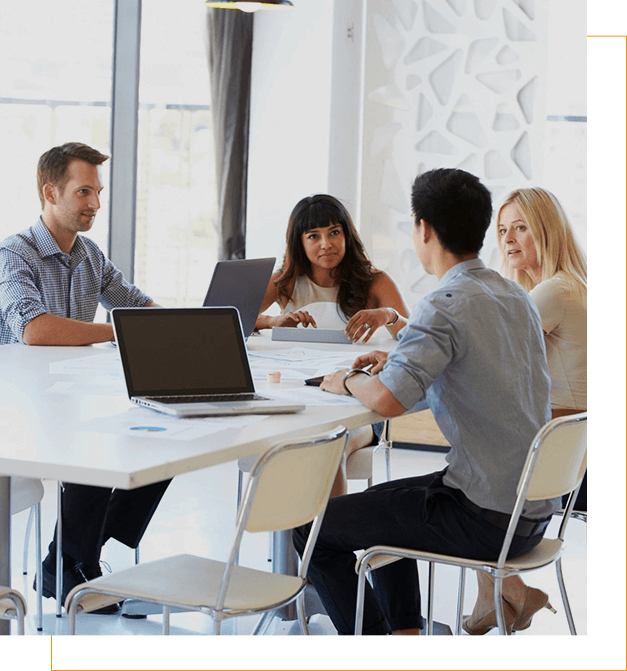 A group of people sitting around a table with laptops.